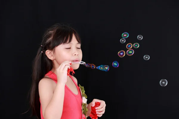 Menina feliz jogar com bolhas de sabão isolado fundo preto — Fotografia de Stock