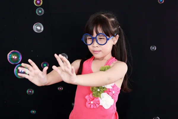 Glückliches Mädchen spielen mit Seifenblasen isoliert schwarzen Hintergrund — Stockfoto