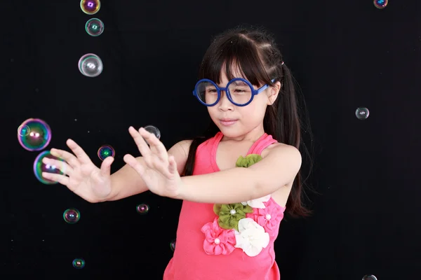 Menina feliz jogar com bolhas de sabão isolado fundo preto — Fotografia de Stock