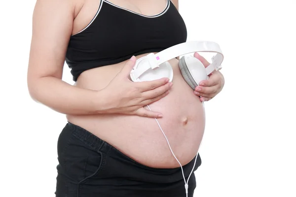 Беременная женщина ласкает живот наушниками — стоковое фото