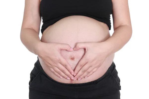 Zwangere vrouw strelen haar buik met hand hart teken op wit — Stockfoto