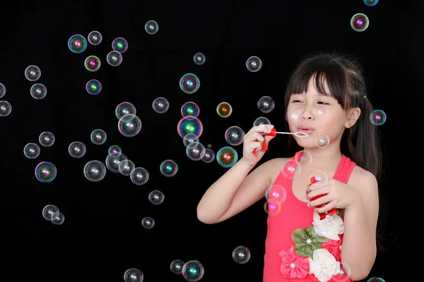 Šťastná dívka hrát s černým pozadím mýdlové bubliny, samostatný — Stock fotografie