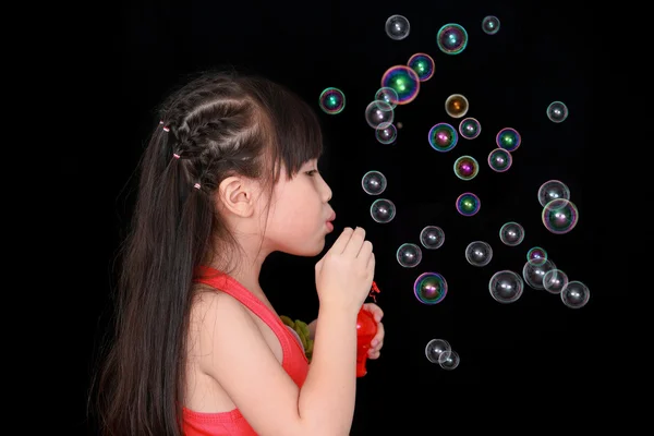 Menina feliz jogar com bolhas de sabão isolado fundo preto — Fotografia de Stock