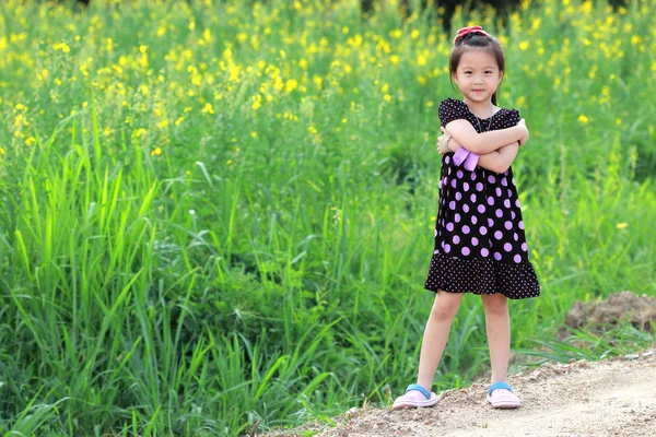 Porträtt av vacker glad liten flicka i ett fält av gula flo — Stockfoto