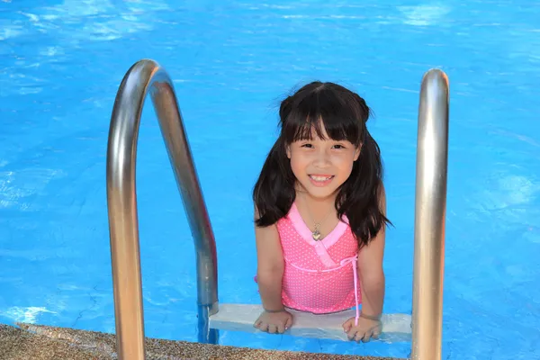 Gadis kecil tersenyum berenang di kolam biru — Stok Foto