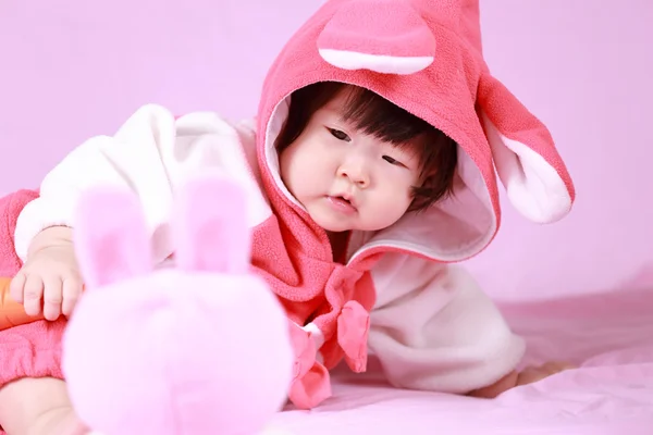 Bambino vestito con orecchie di coniglio pasquale con carota — Foto Stock