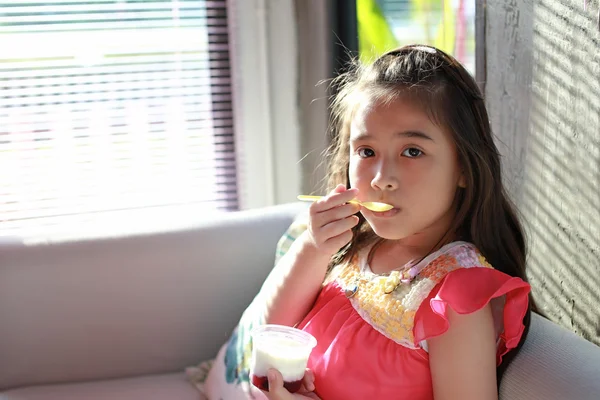 Азіатська маленька дівчинка читає йогурт — стокове фото
