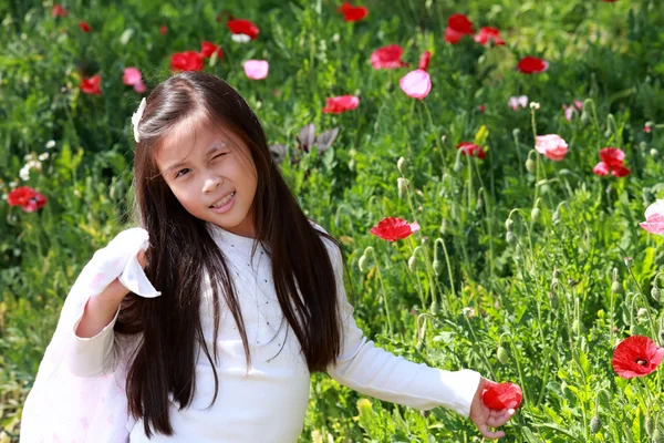 Sorridente asiatica bambina con lunghi capelli scuri sul campo di papavero — Foto Stock