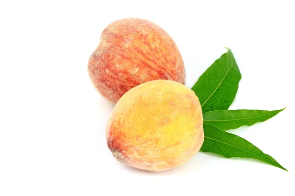Персиковые фрукты с зелеными листьями на белом фоне — стоковое фото