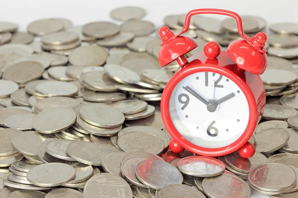 Rode klok verblijf op munten. tijd is geld begrip — Stockfoto
