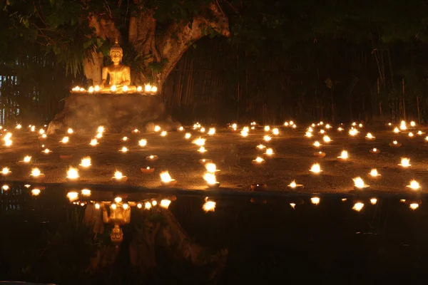 Statua di Buddha riflettere sull'acqua con candele fuoco accensione — Foto Stock
