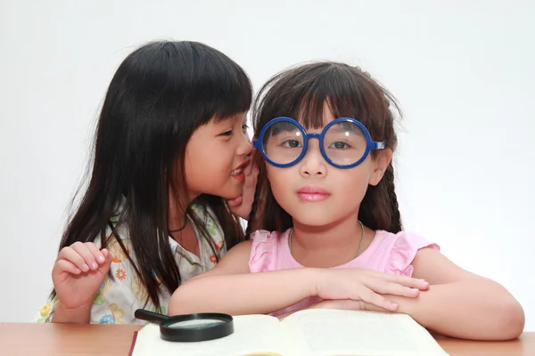 Милая маленькая азиатская девочка шепчет что-то своей сестре — стоковое фото