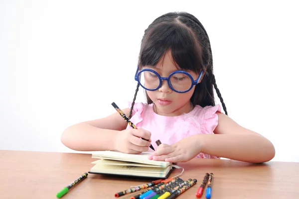 Asiatische kleine Mädchen zeichnen auf einem Buch isoliert auf einem über weißen Backgr — Stockfoto