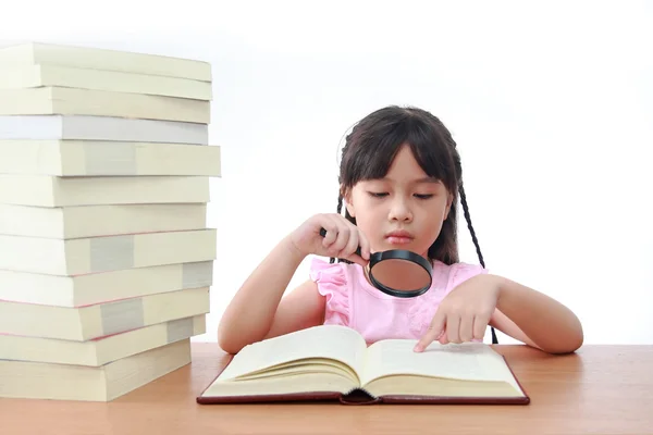 Asian little girl reading a book with magnifying glass isolated — Stock Photo, Image