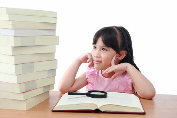 Asiatiska liten flicka som läser en bok med förstoringsglas isolerade — Stockfoto