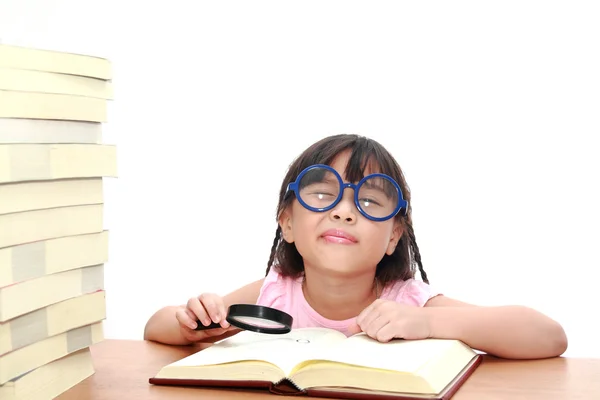 Asian little girl reading a book with magnifying glass isolated — Stock Photo, Image