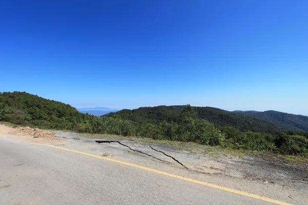 Strada di asfalto rotta nella natura — Foto Stock