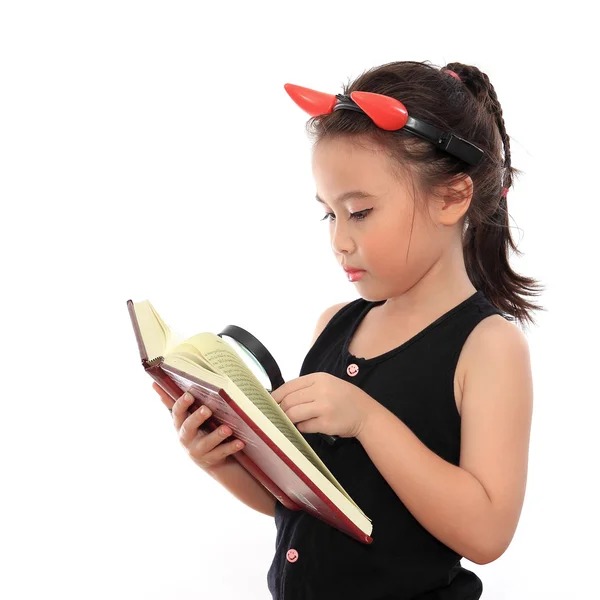 Beautiful little asian girl reading book with magnifying glass — Stock Photo, Image