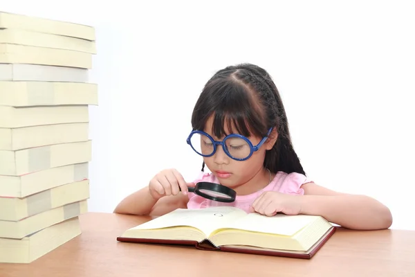 Asian little girl reading a book with magnifying glass — Stock Photo, Image