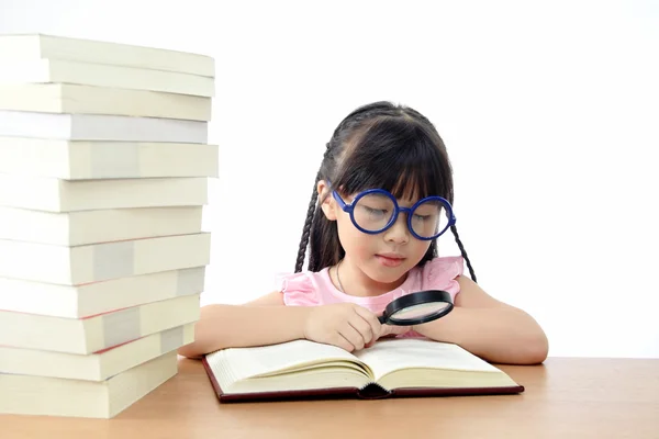 Estudante menina leitura livro com lupa — Fotografia de Stock