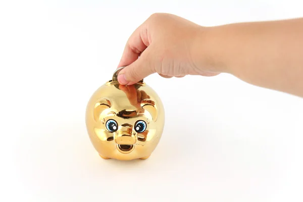 Kid hand putting a coin in a piggy bank — Stock Photo, Image