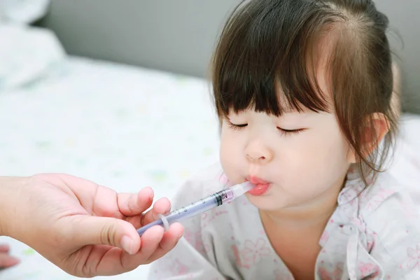 Madre dando a sua figlia sciroppo liquido — Foto Stock