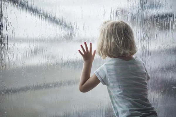 Menina olhando gotas de chuva na janela — Fotografia de Stock