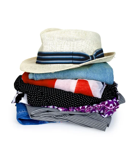 Hög med färgglada kläder med en hatt över vit bakgrund Royaltyfria Stockfoton