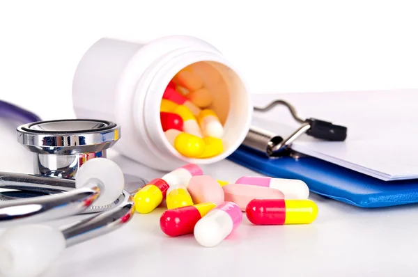 Opakowania tabletek i stetoskop na białym tle — Zdjęcie stockowe