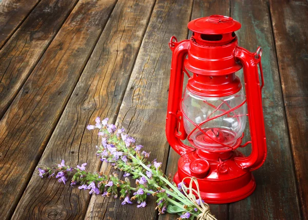 Red vintage kerosene lamp, and sage flowers on wooden table. fine art concept. — Stock Photo, Image