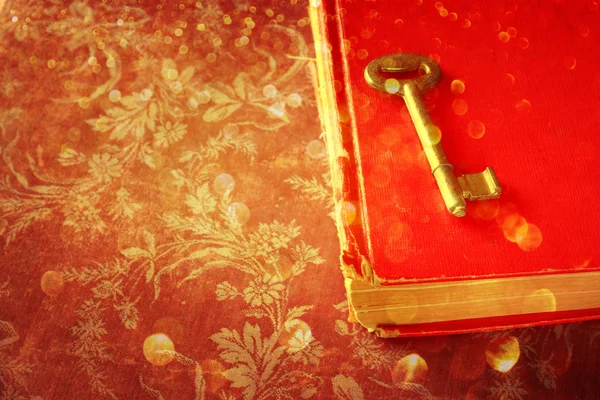 Röda boken och vintage nyckel och gyllene glitter ljus — Stockfoto