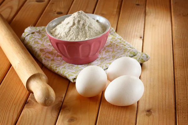 Harina en tazón con huevos y rodillo sobre mesa de madera — Foto de Stock