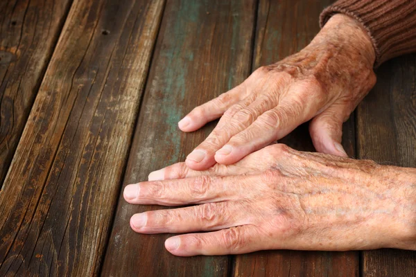 Close up van oudere mannelijke handen op houten tafel — Stockfoto
