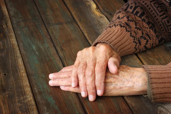 Close up of elderly male hands on wooden table — Stock Photo, Image