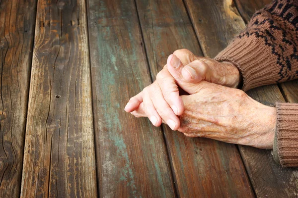Primer plano de manos ancianas masculinas sobre mesa de madera —  Fotos de Stock