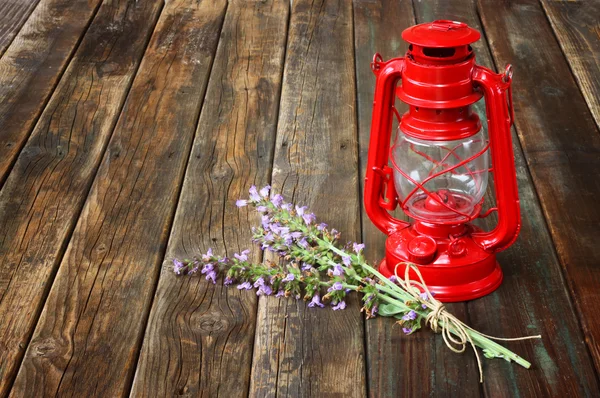 Lámpara de queroseno vintage rojo, y flores de salvia en la mesa de madera. concepto de arte fino . — Foto de Stock