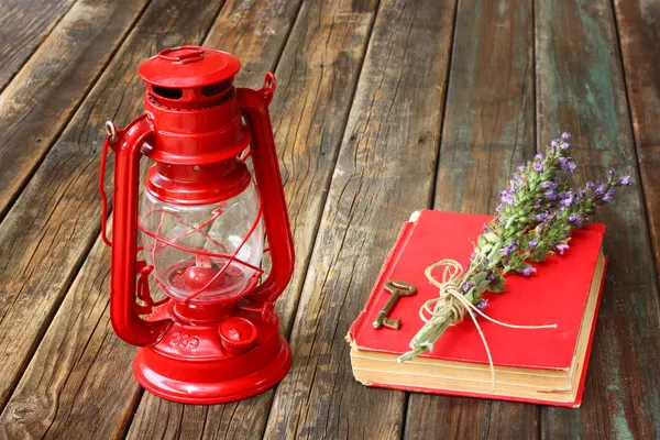 Linterna roja vintage y libro rojo sobre mesa de madera — Foto de Stock