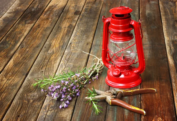 Lámpara de queroseno vintage rojo, salvia y romero sobre mesa de madera. concepto de arte fino . — Foto de Stock