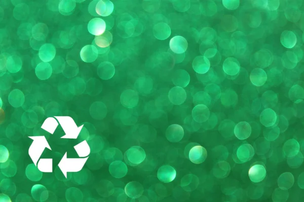 White recycle sign and green glitter lights background. defocused lights. — Stock Photo, Image