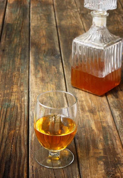 Verre et bouteille d'alcool comme le scotch, le bourbon, le whisky ou le brandy sur une table en bois — Photo