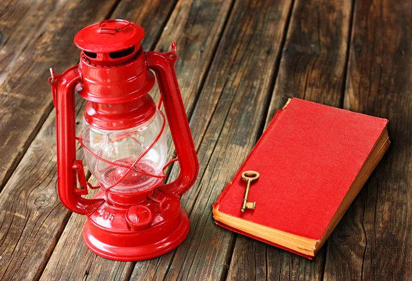 Rote Vintage-Lampe und rotes antikes Buch auf Holztisch. Vintage Stillleben Design. — Stockfoto