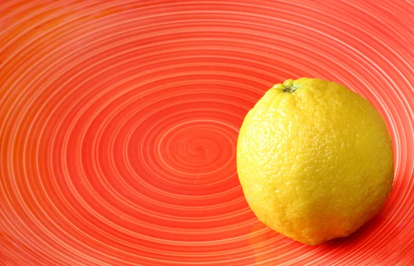 Limone fresco su piatto rosso con motivo a spirale  . — Foto Stock