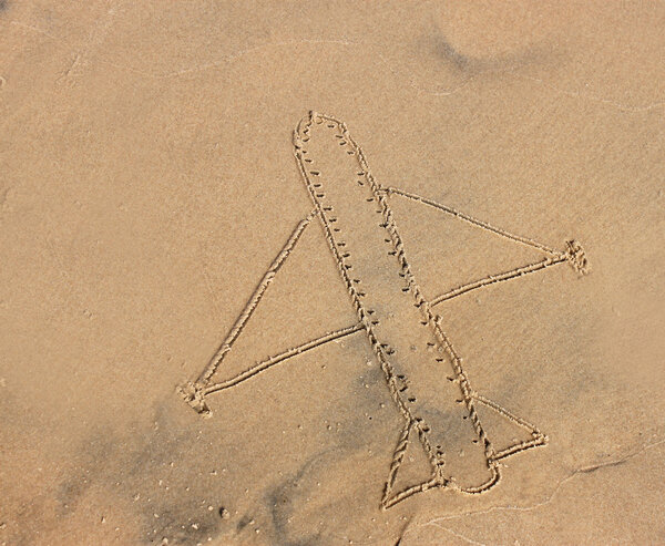 Airplane drawn on sea sand, vacation or holiday concept