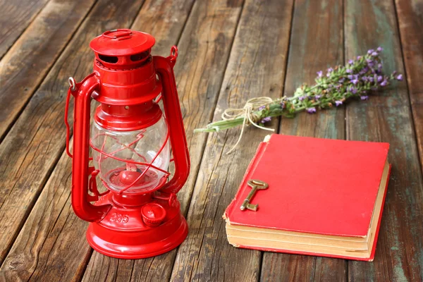Lanterna vermelha vintage e livro vermelho na mesa de madeira — Fotografia de Stock