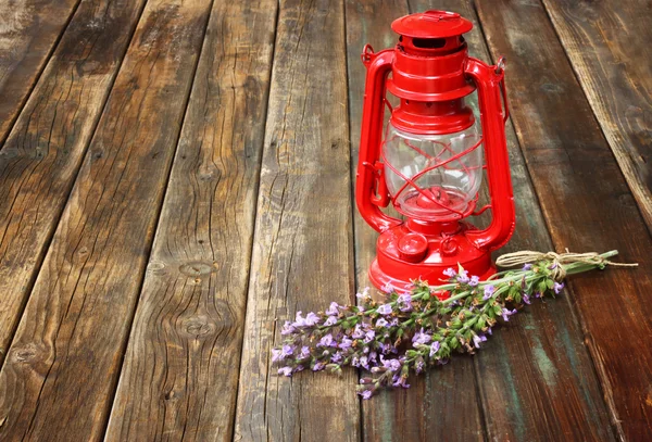 Piros vintage petróleumlámpa, és bölcs virágok a fából készült asztal. művészeti koncepció. — Stock Fotó