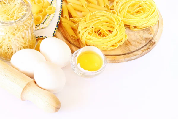 Pâtes, oeufs et rouleau à pâtisserie en bois isolés sur fond blanc — Photo