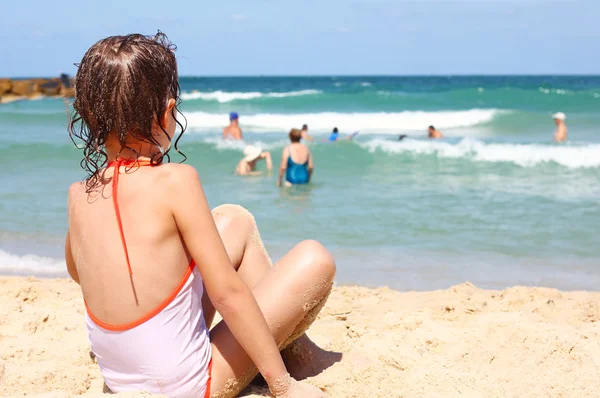A menina está sentada em uma praia — Fotografia de Stock