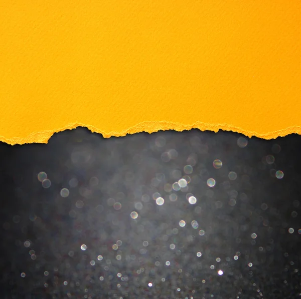 Luces bokeh negras y papel desgarrado naranja —  Fotos de Stock