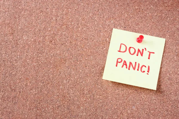 Cork board with pinned yellow note and the phrase "dont panic" — Stock Photo, Image