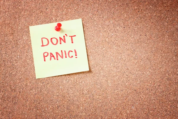 Cork bord met vastgezette gele opmerking en de zin "don't panic" — Stockfoto